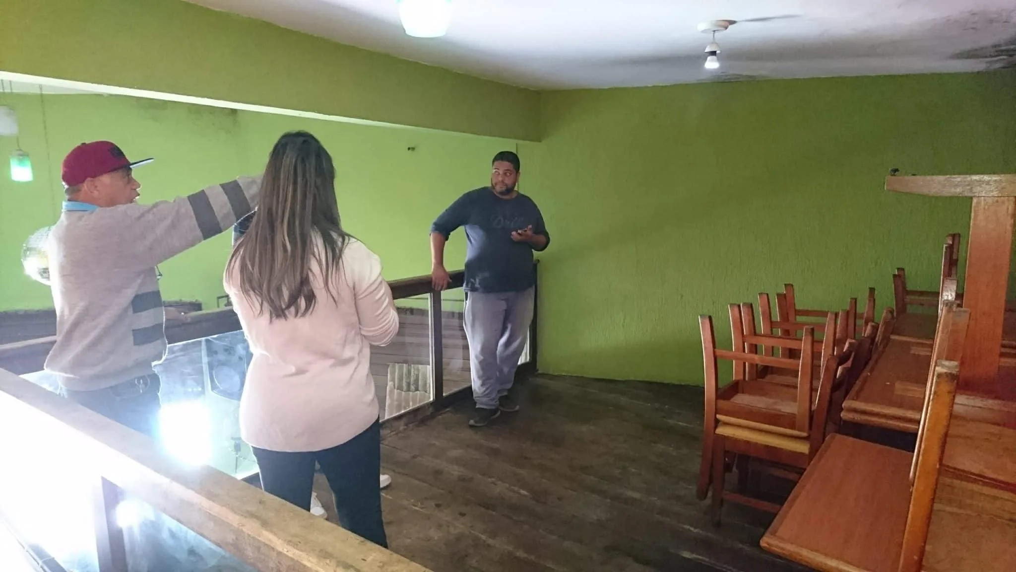 Estado do mezanino antes da intervenção Mezanino antes da reforma com piso de madeira, paredes verdes e mobiliário existente