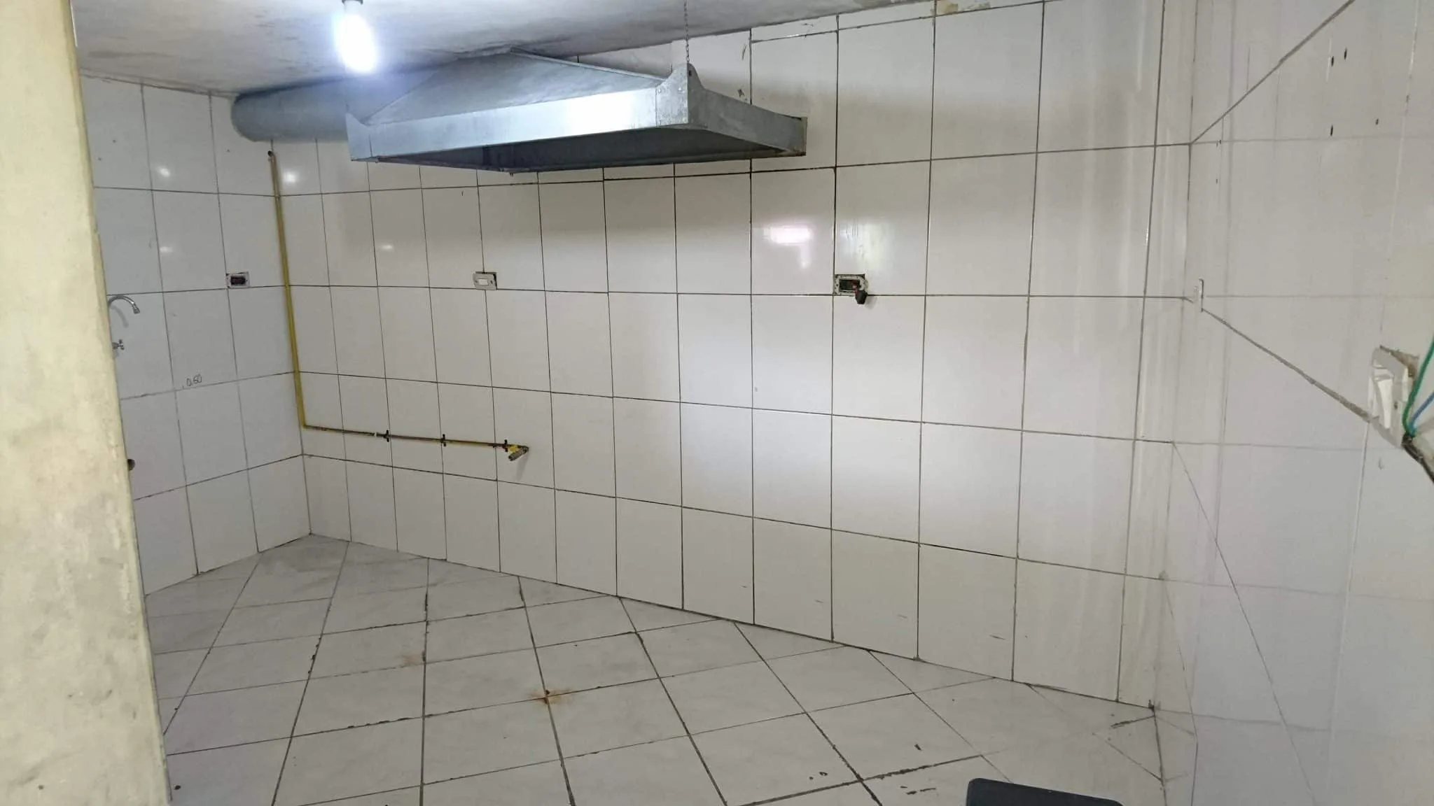 Cozinha durante a reforma do bar Cozinha durante a reforma com revestimento cerâmico branco e coifa instalada