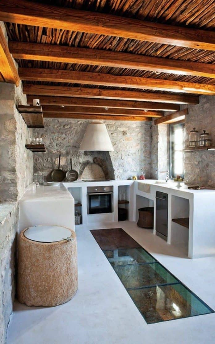 Cozinha rústica com móveis de alvenaria e chão de vidro com vista para adega