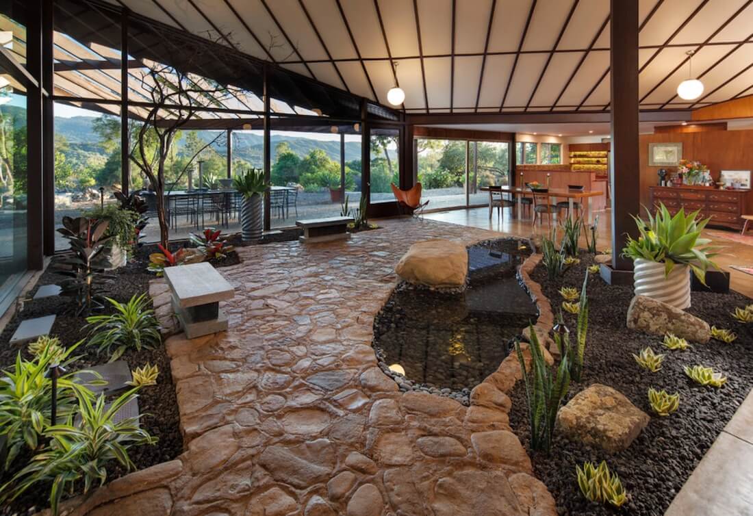 Espaço interno com jardim e chão de pedra.