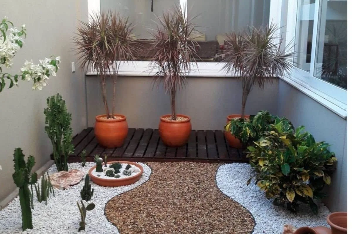 Jardim de inverno pequeno com pedras, vasos e caminho decorativo