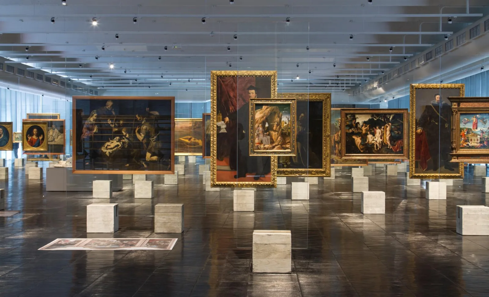 Lina Bo Bardi: biografia, obras e legado na arquitetura 3 Cavaletes de cristal projetados por Lina Bo Bardi no MASP, com pinturas suspensas em placas de vidro apoiadas sobre bases de concreto.