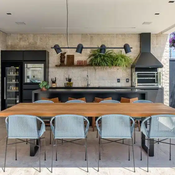 Área gourmet com churrasqueira, bancada e mesa Área gourmet com churrasqueira, bancada linear e grande mesa de refeições
