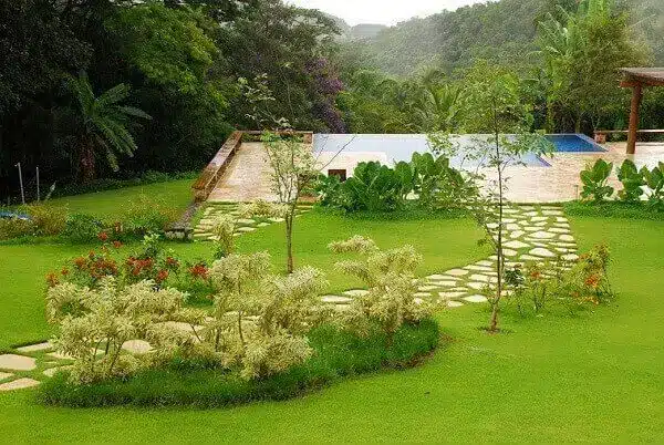 7 Ideias para Decorar a Entrada de Chácara 7 Área externa da casa de chácara com jardim e piscina.