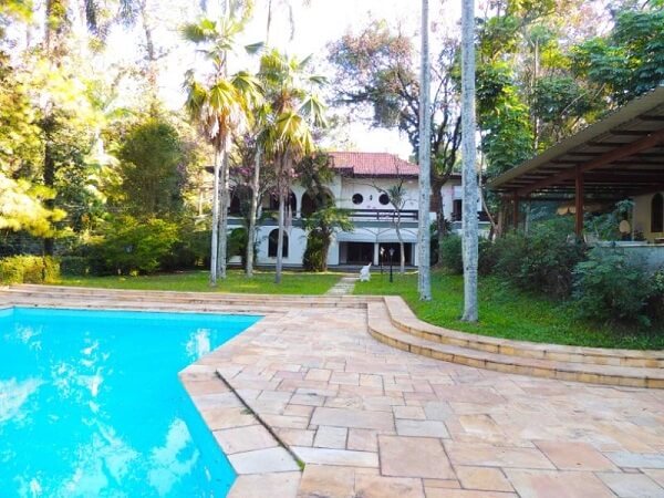 7 Ideias para Decorar a Entrada de Chácara 13 Piso de pedra natural e arbustos naturais verdes na decoração da casa de chácara.