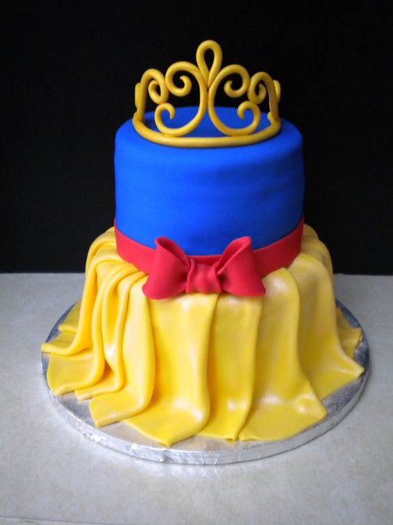 11 Ideias de Bolo de Branca de Neve para Festas Inesquecíveis 12 Bolo representando o vestido da Branca de Neve com detalhes texturizados, laços e coroa.