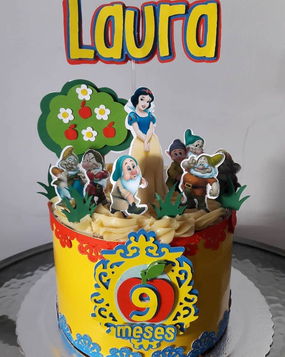 11 Ideias de Bolo de Branca de Neve para Festas Inesquecíveis 20 Bolo coberto de chantilly com placas personalizadas temáticas no topo, criando degrade.
