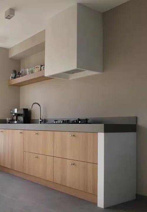 Cozinha linear com bancada escura, base clara e portas de madeira natural