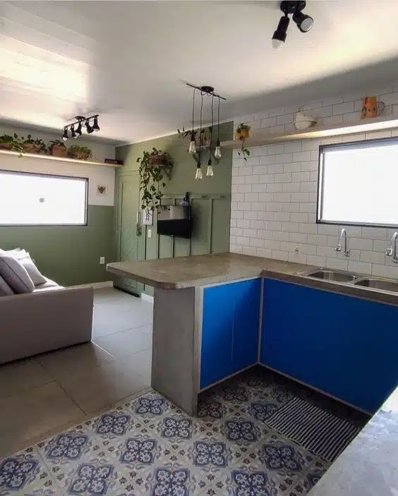 Cozinha em L com portas azuis e bancada alta separando a cozinha da sala