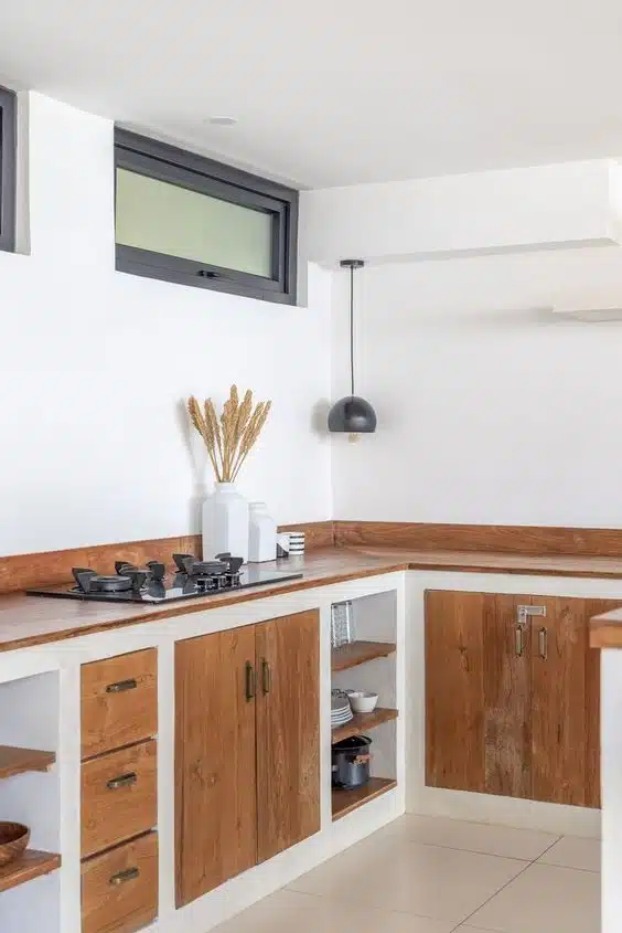 Cozinha em L com base branca, portas de madeira, nichos abertos e cooktop
