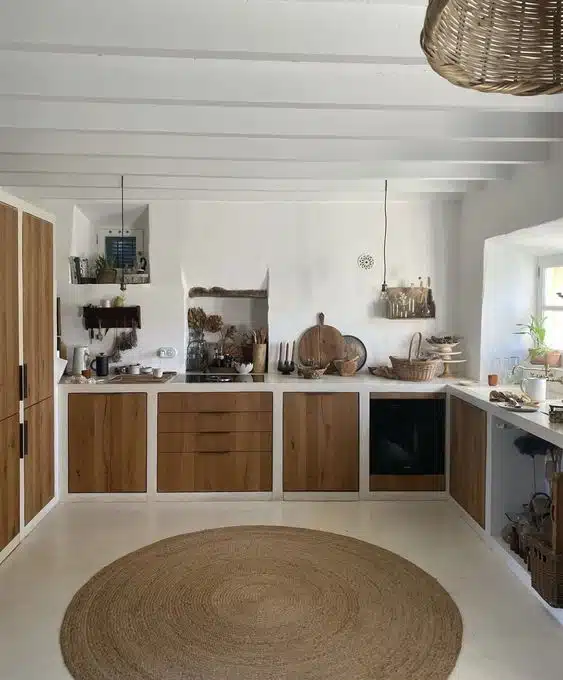 Cozinha branca com portas de madeira natural, nichos e tapete redondo de fibra