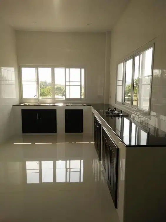 Cozinha ampla e clara com bancadas escuras e portas inferiores pretas