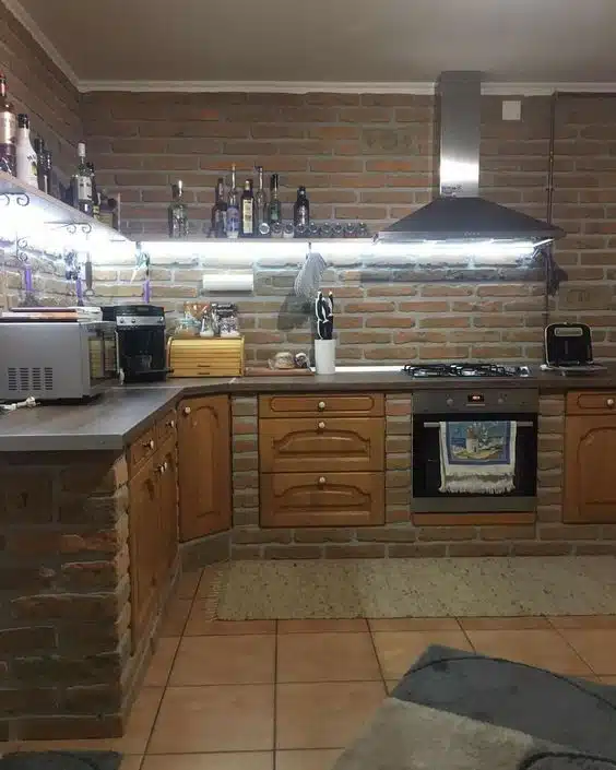 Cozinha rústica com parede e base de tijolos aparentes, portas de madeira e coifa metálica