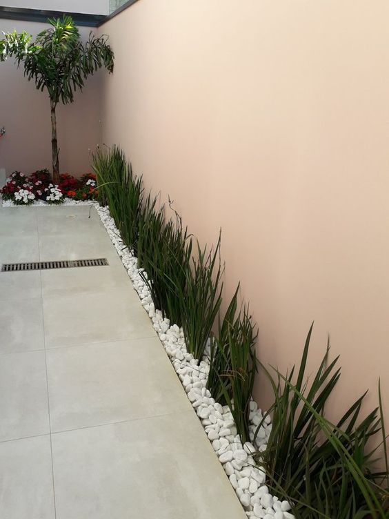 14. Pedras brancas dão um charme a mais nesse canteiro, que ainda conta com a presença de espécies florais em sua composição.