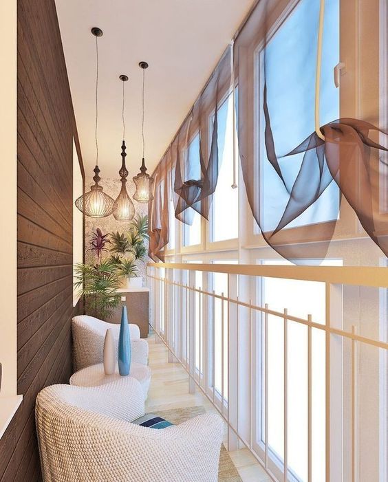 Cortinas dão um estilo a mais à sua varanda e, em conjunto com os lustres, ficou tudo muito bem decorado; a sacada de vidro com acabamento na cor branca contribuiu para isso