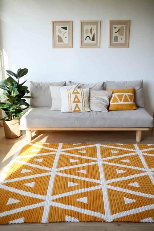 11 Ideias de Tapete de Crochê para Sala que Você Vai Adorar 14 Em cores vibrantes e formas geométricas, o tapete retangular de crochê combina com as capas das almofadas.