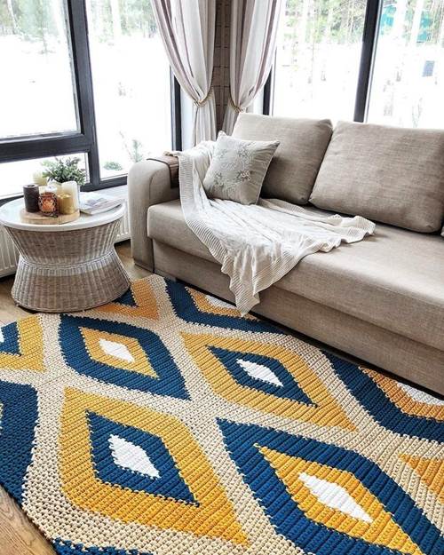 11 Ideias de Tapete de Crochê para Sala que Você Vai Adorar 18 Nesse tapete feito à mão, os desenhos foram feitos com linha de cores complementares, como o azul royal e o mostarda. A base é neutra, como o restante da decoração.