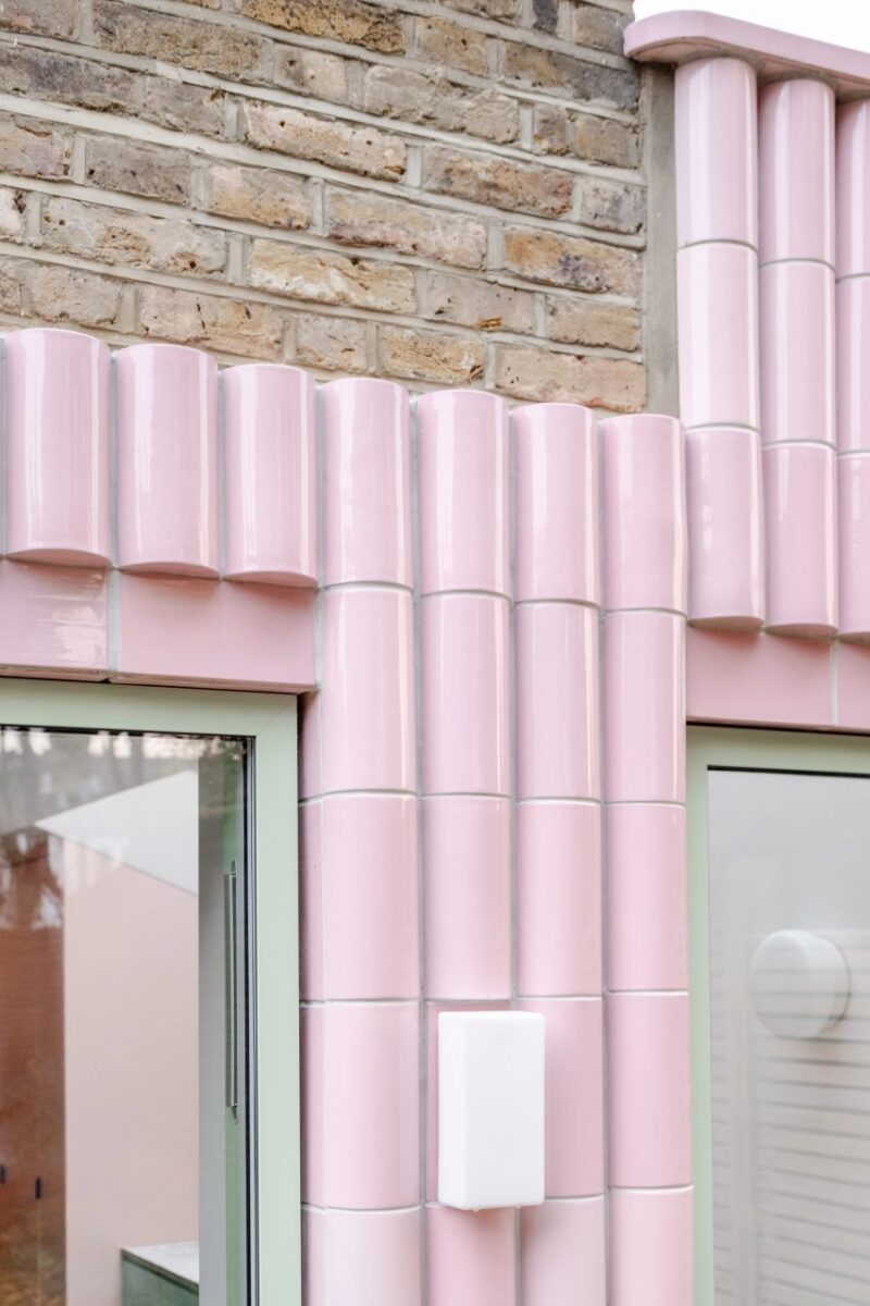 Extensão vibrante da Beacon House encanta com azulejos rosa. 3 Frames de janela verde claro contrastam com o rosa