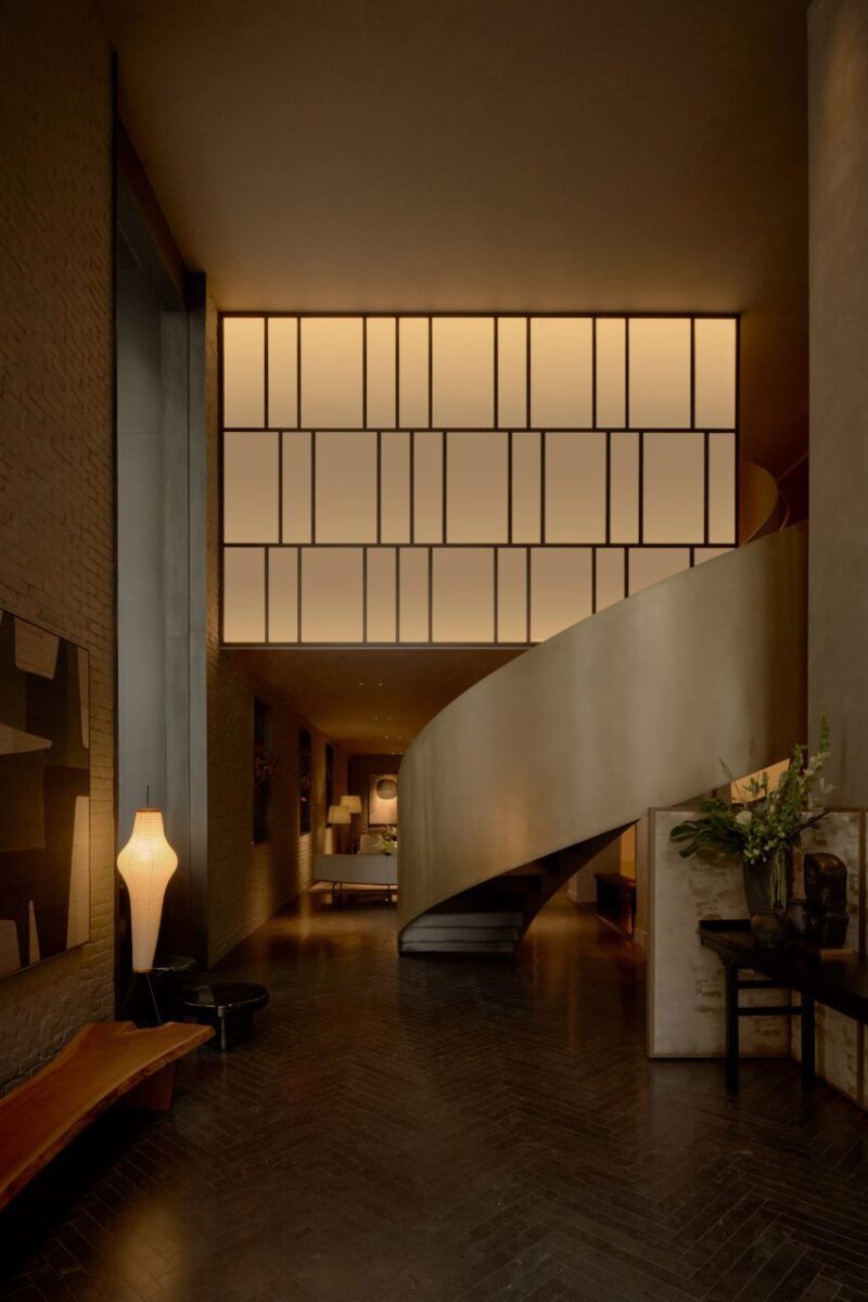Interiores sofisticados e minimalistas no novo hotel de NYC. 2 Um átrio do hotel com uma escada espiral pintada de bronze como peça central.