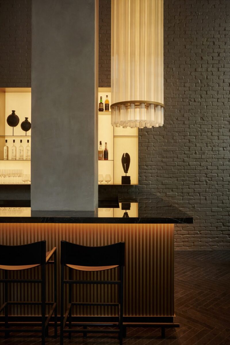 Interiores sofisticados e minimalistas no novo hotel de NYC. 4 Bar com balcão preto brilhante e um design elegante que acrescenta à altura do espaço.