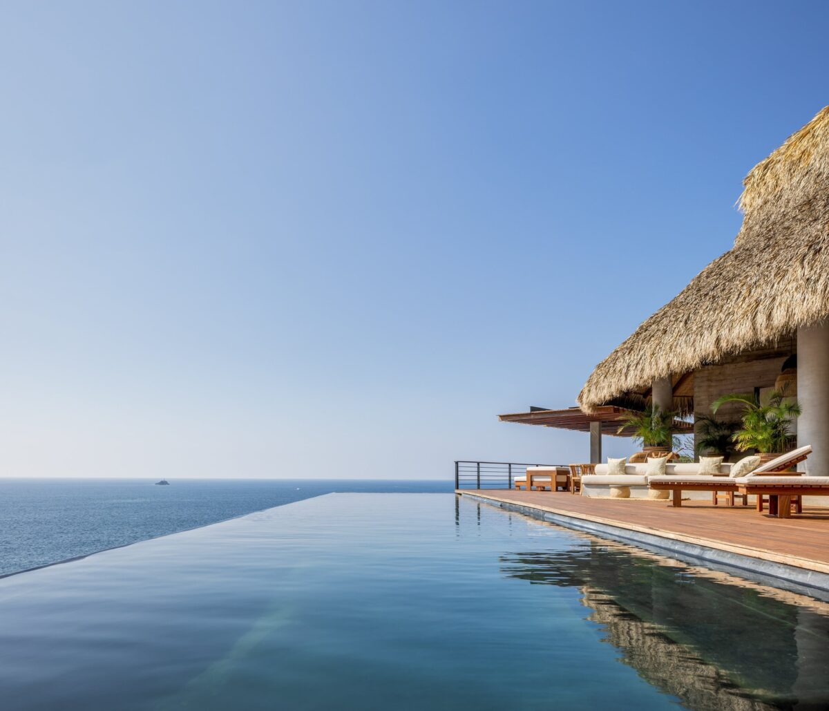 Arquitetura Sustentável: A Casa Acantilado no México 9 Imagem do interior da sala, com paredes de concreto exposto, proporcionando uma vista impressionante do deck e da piscina.