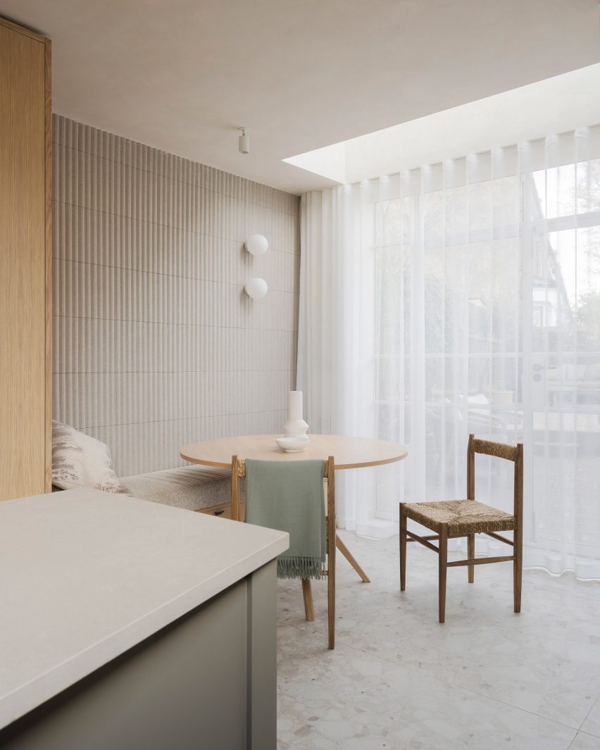 Detalhe do espaço de café da manhã na cozinha, decorado com azulejos estriados e iluminação natural que entra pelo céu.