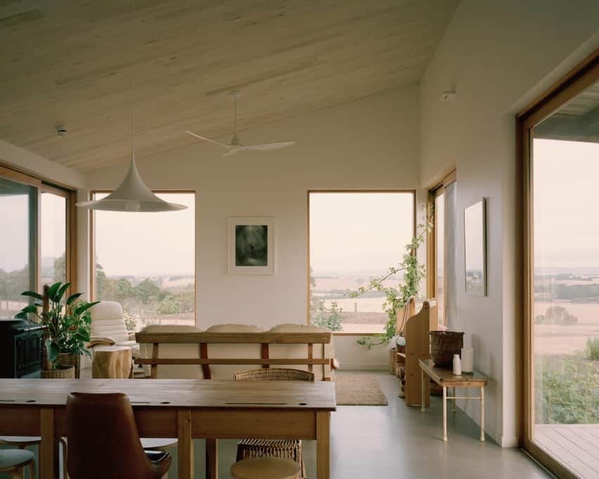 Casa Sustentável e Autossuficiente: A Inovadora Residência Off-Grid. 3 Um espaço interno que mostra a sala de estar, a sala de jantar e a cozinha em um dos lados do U da casa.