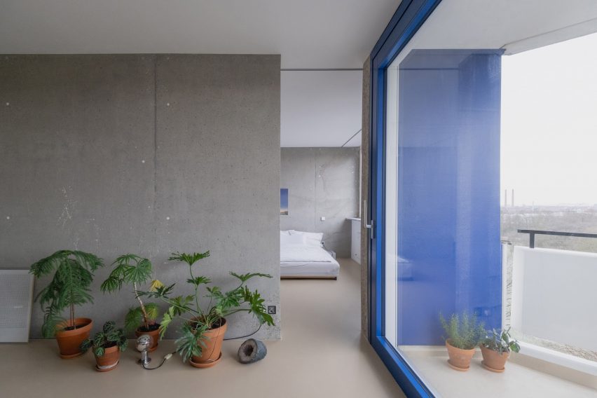 Transformação impressionante de apartamento em Colônia. 2 Vista da sala de estar para o quarto através de uma abertura em uma parede de concreto.