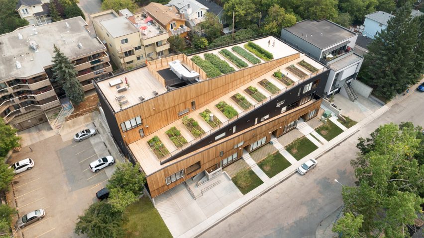 Jardins Inovadores Transformam Habitação Multifamiliar em Calgary. 2 Vista do edifício GROW em destaque, apresentando seu acabamento em madeira verde e as janelas emolduradas de preto.