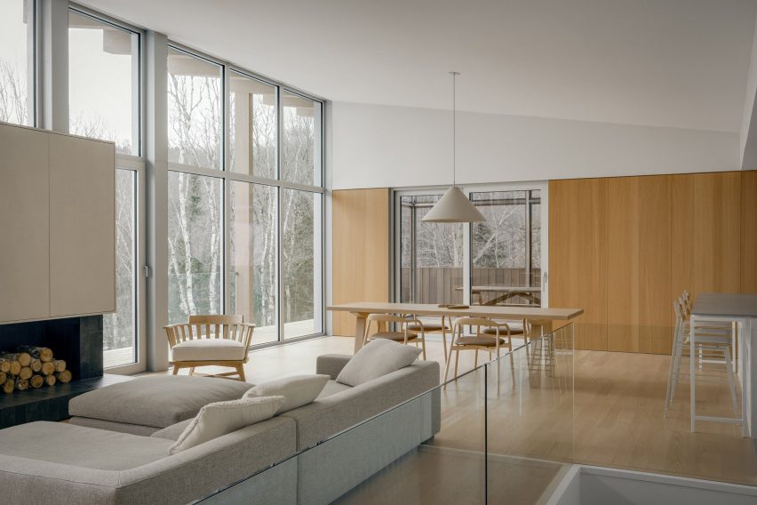 5 soluções criativas para casas de madeira com telhado inclinado. 3 Imagem do nível superior da residência, com sala de estar, sala de jantar e cozinha em plano aberto.