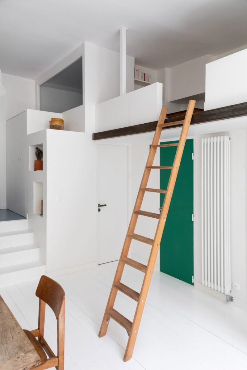 Interiores surpreendentes que se destacam com escadas criativas. 3 Uma escada de madeira propensa a um mezanino no apartamento Timbaud, em Paris, decorada por Isabelle Heilmann. O ambiente possui uma mesa de jantar antiga e um balanço na sala.