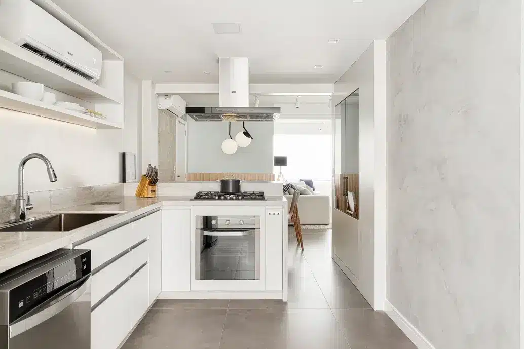 Cozinha com bancadas de porcelanato e piso imitando cimento queimado. A cor branca na cozinha traz sensação de amplitude (Projeto: Gabriella Gochinski)