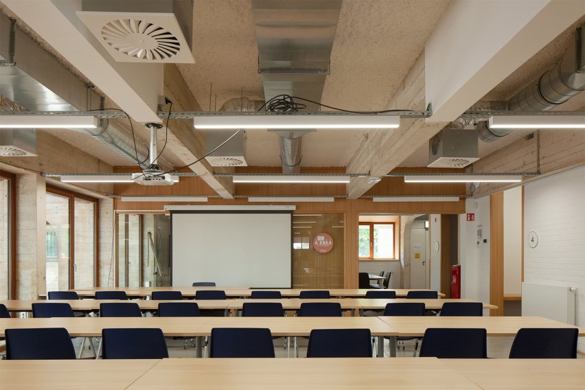 Transformação impressionante de correio brutalista em centro de aprendizado. 3 Sala de reuniões dentro do centro de aprendizado, com acabamentos em concreto exposto e paredes de tijolo.