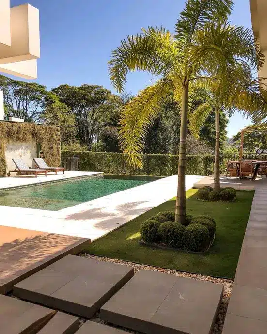 Revestimento de muros e paredes externas: dicas para escolher o melhor 10 7 Patio de uma casa com piscina e revestimento natural de plantas.