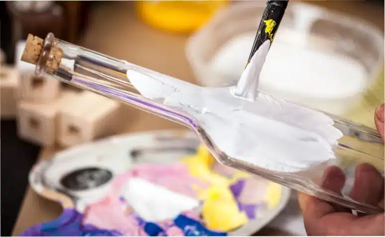 A imagem mostra uma variedade de tintas para vidro em várias tonalidades, destacando o tema do artigo.