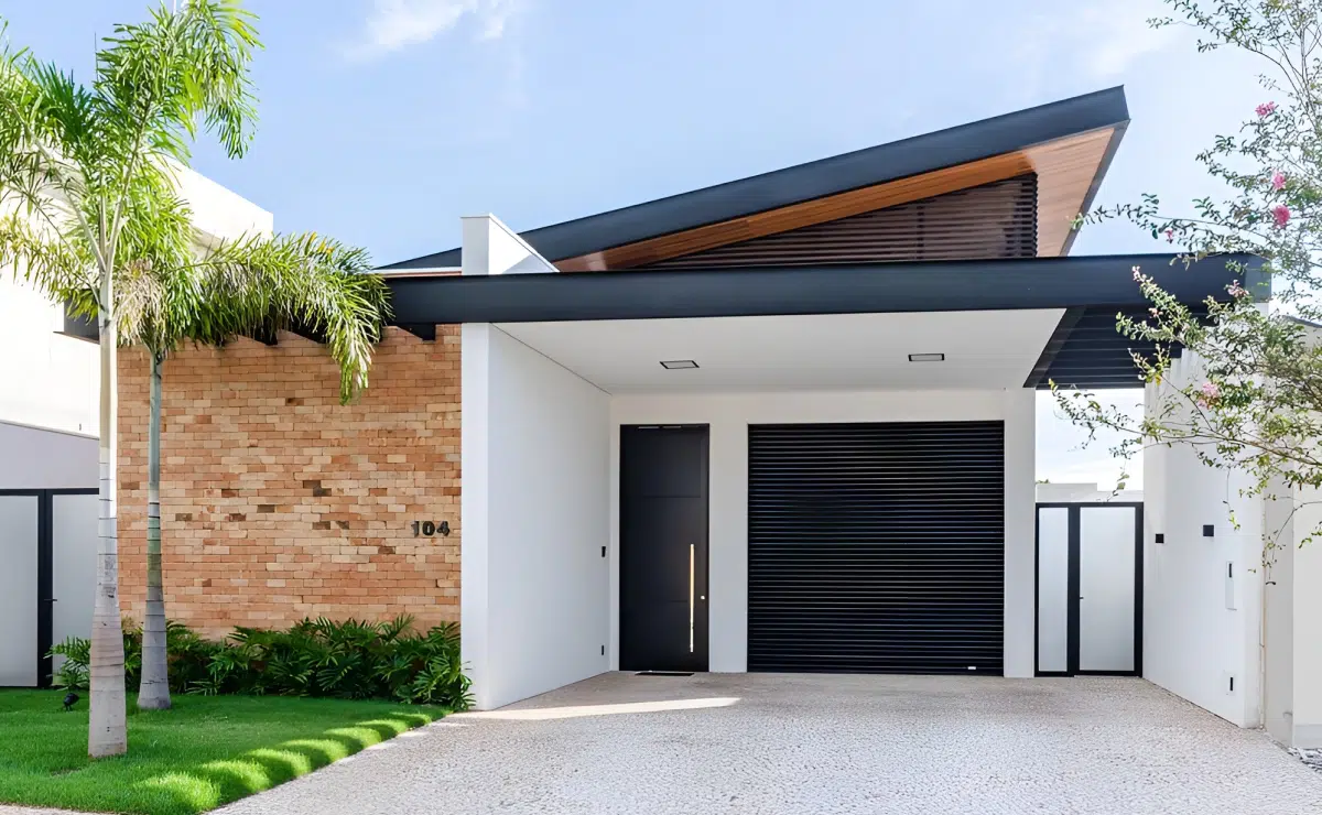Fachada de casa simples com garagem, tijolo e jardim Fachada de casa térrea com garagem, tijolo aparente, jardim frontal e cobertura contemporânea