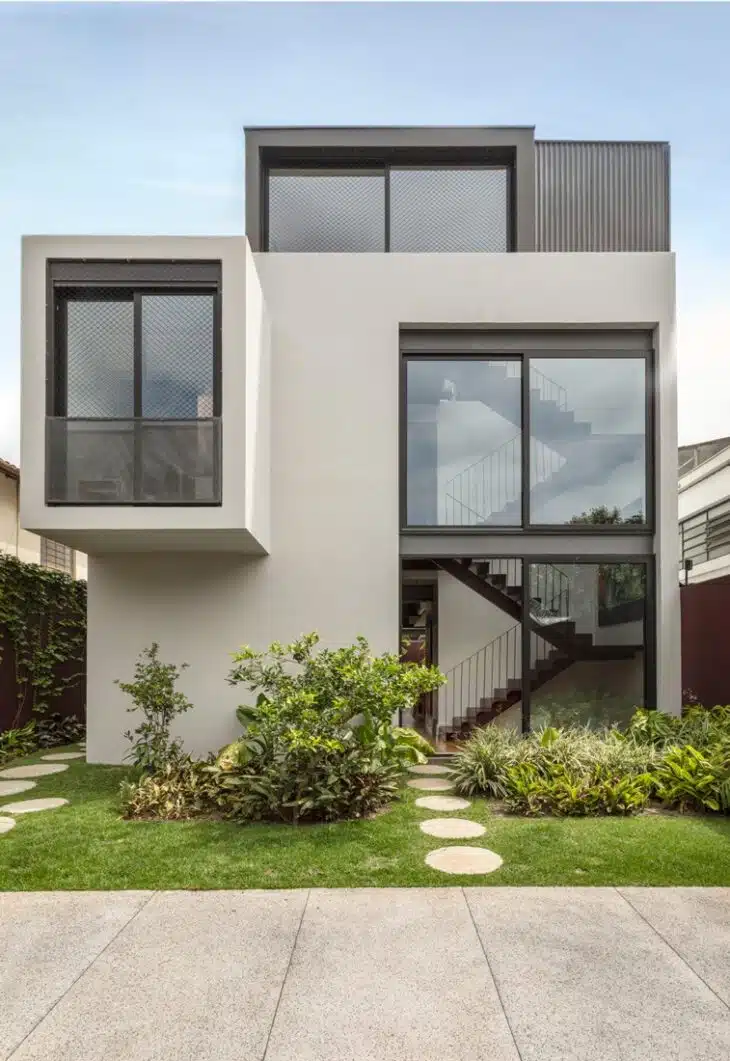 Sobrado simples com linhas contemporâneas Sobrado contemporâneo claro em terreno estreito com grandes janelas escuras e jardim frontal