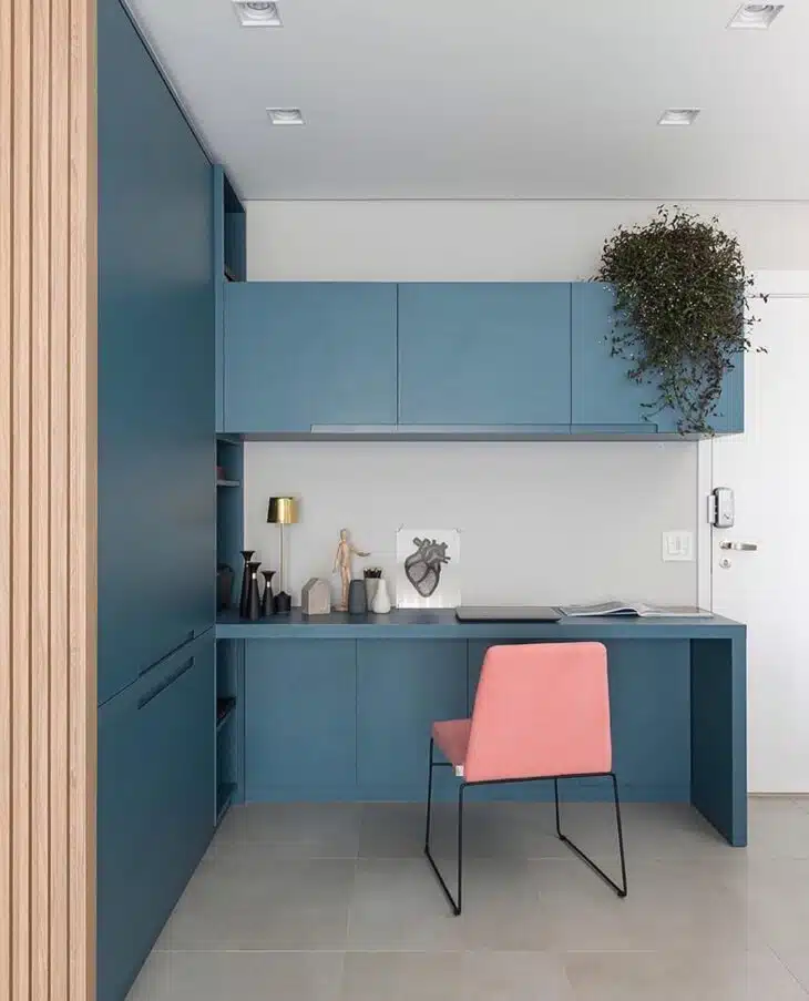 Cadeira rosa contrastando com marcenaria azul no quarto