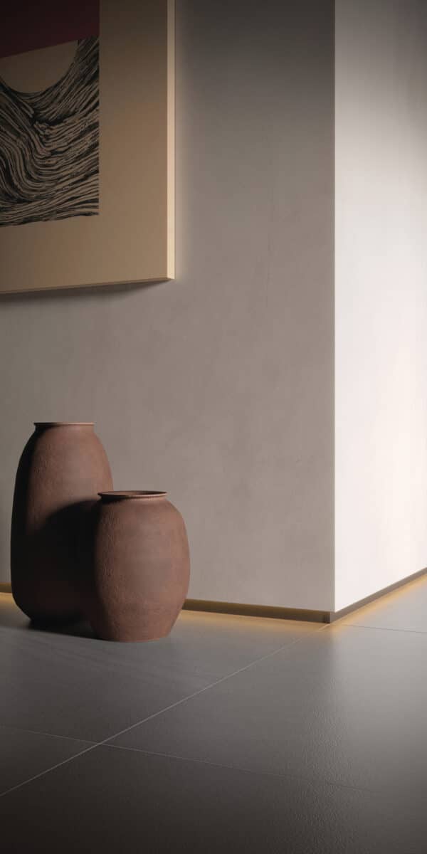 Área com paredes claras, rodapé invertido de alumínio, vasos marrons em diferentes tamanhos e um quadro na parede clara. (Projeto: Portobello)
