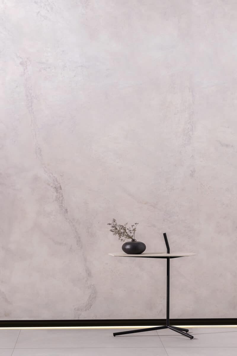 Rodapé Invertido: Conheça o Formato, Vantagens e Como Instalar 2 Ambiente com parede acinzentada, rodapé invertido preto e uma mesa lateral pequena com um vaso decorativo em cima. (Projeto: Portobello)