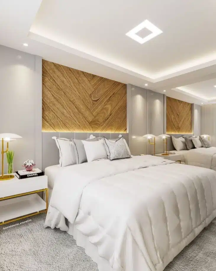 Quarto moderno com iluminação embutida, painel de madeira e luminárias laterais junto à cama