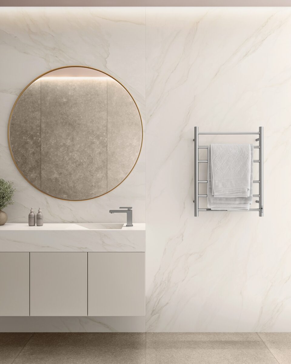 Porcelanato Carrara: A beleza do mármore com as vantagens do revestimento 10. 10 Detalhe de banheiro com porcelanato carrara na parede. Há uma bancada, um espelho redondo e um toalheiro elétrico.