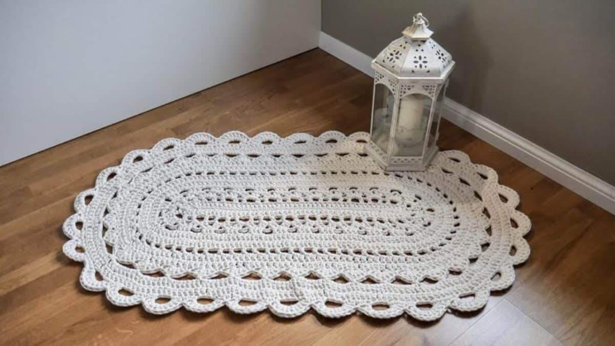 Imagem de um tapete de crochê bege, utilizado em um ambiente bem decorado.
