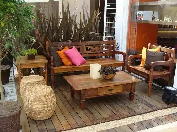 Varanda com móveis de demolição que proporcionam um espaço bonito e confortável, decorado com almofadas coloridas e bancos de palhinha.