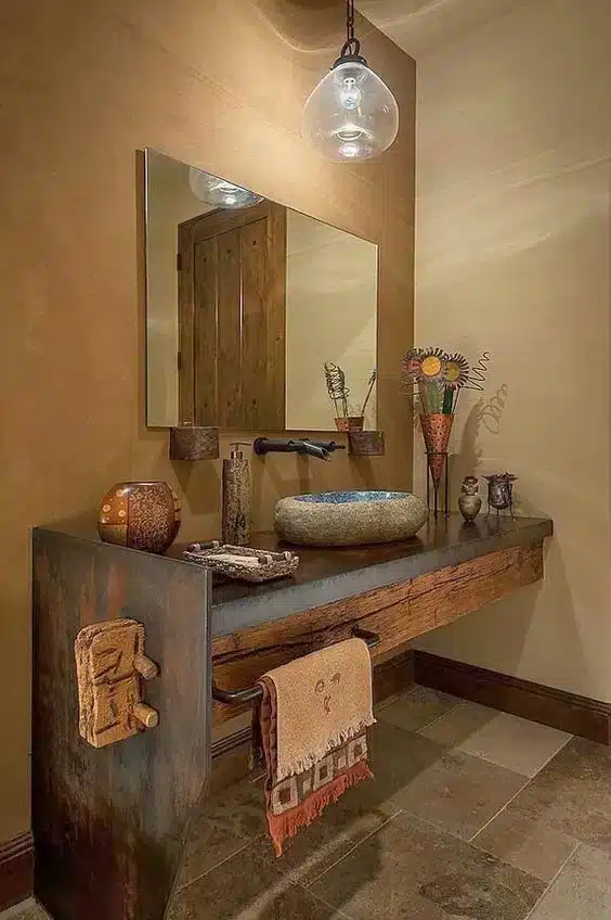 Lavabo rústico onde móveis de pinho se misturam com ardósia, criando um ambiente com uma vibração inspirada na rusticidade.