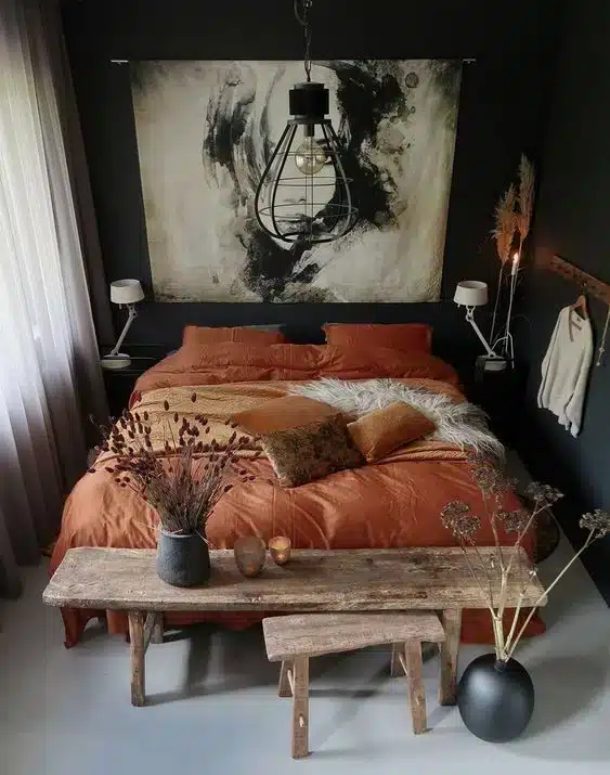 Quarto rústico que utiliza móveis de madeira de demolição, com bancos ao pé da cama servindo como suporte para objetos de decoração.