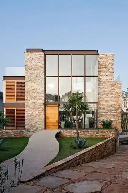 9 Inspirações de Fachadas de Casa para Todos os Estilos 7 Fachada em harmonia com materiais rústicos, visando uma captação natural da luz solar.