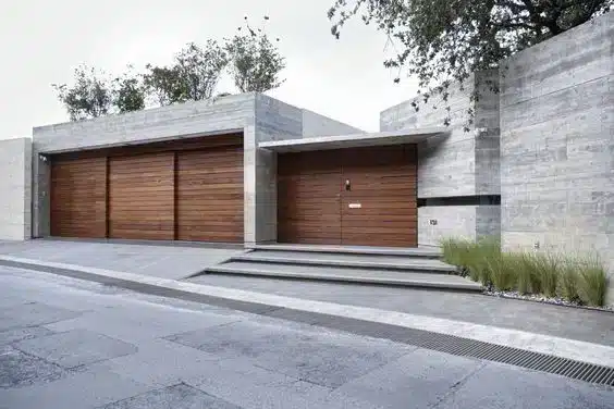9 Inspirações de Fachadas de Casa para Todos os Estilos 9 Fachada de casa com estruturas alinhadas de concreto e um portão de madeira.