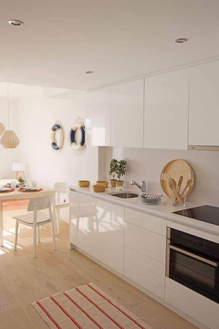 Pequeno apartamento de praia: decoração que inspira e relaxa 2 Foto da varanda do apartamento, com mesa e cadeiras brancas.