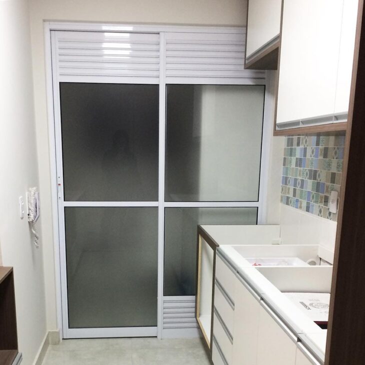Alternativas Efetivas para Dividir a Cozinha da Lavanderia 1 Porta de vidro com adesivo jateado para disfarçar itens de limpeza na lavanderia.